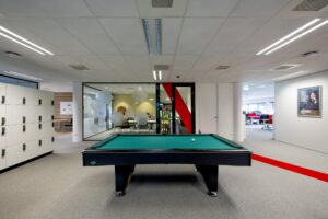 Pooltafel in een moderne kantoorgang aan de H.J.E. Wenckebachweg met zicht op vergaderruimte en lockers.